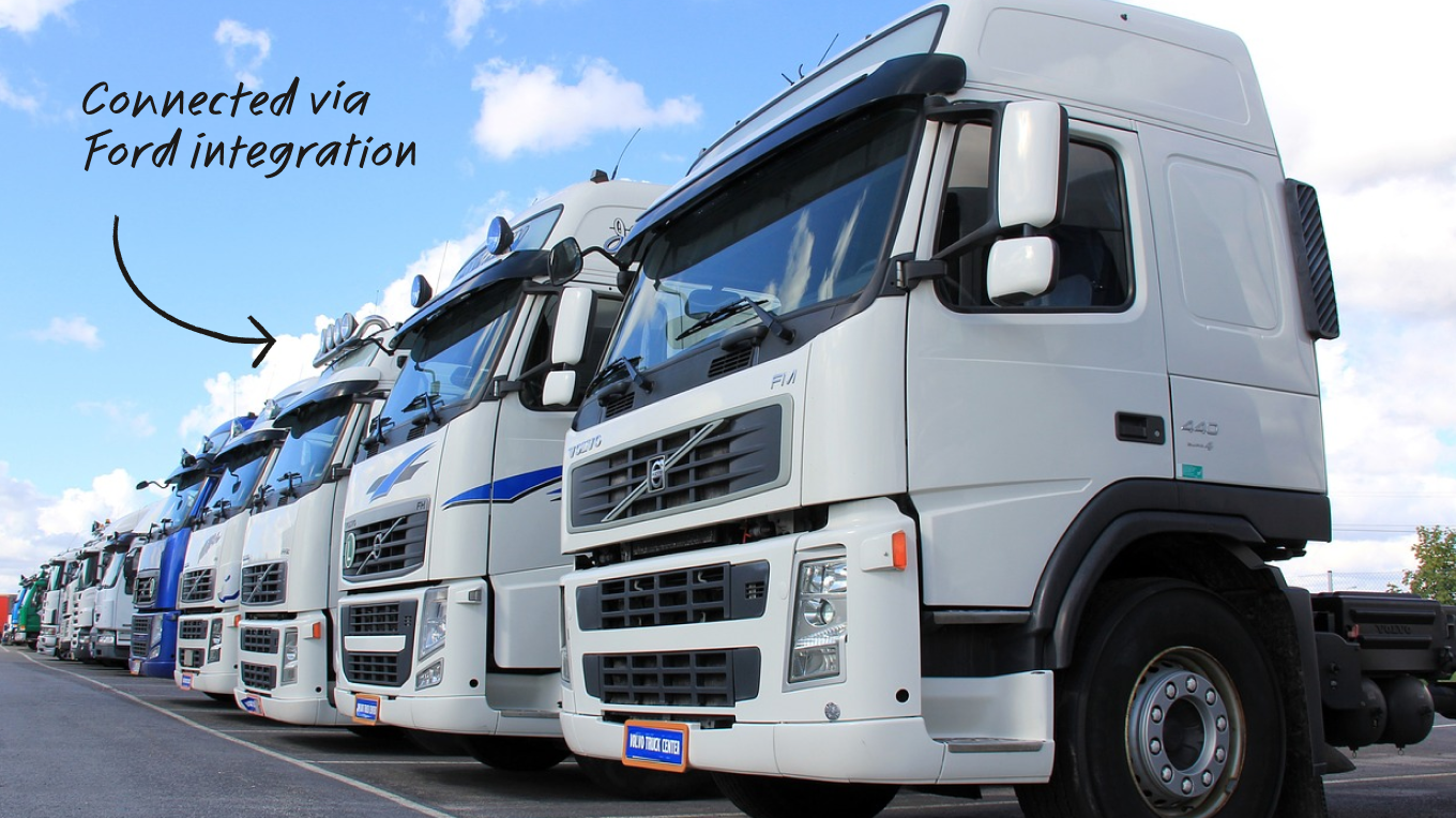 A row of white Volvo trucks parked outdoors, with text reading "Connected via Ford integration" and an arrow.
