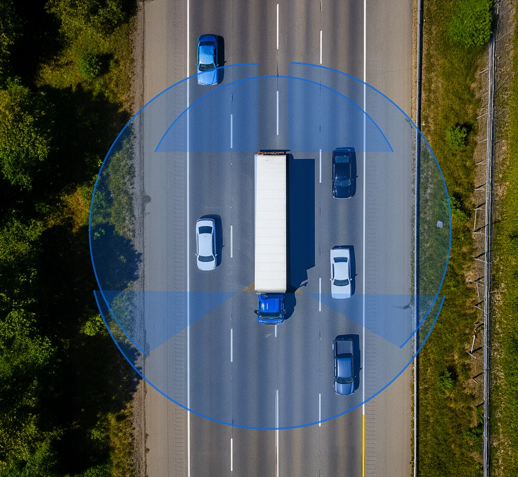 Aerial view of highway with blue truck pulling white trailer surrounded by cars, highlighted by blue circular overlay.