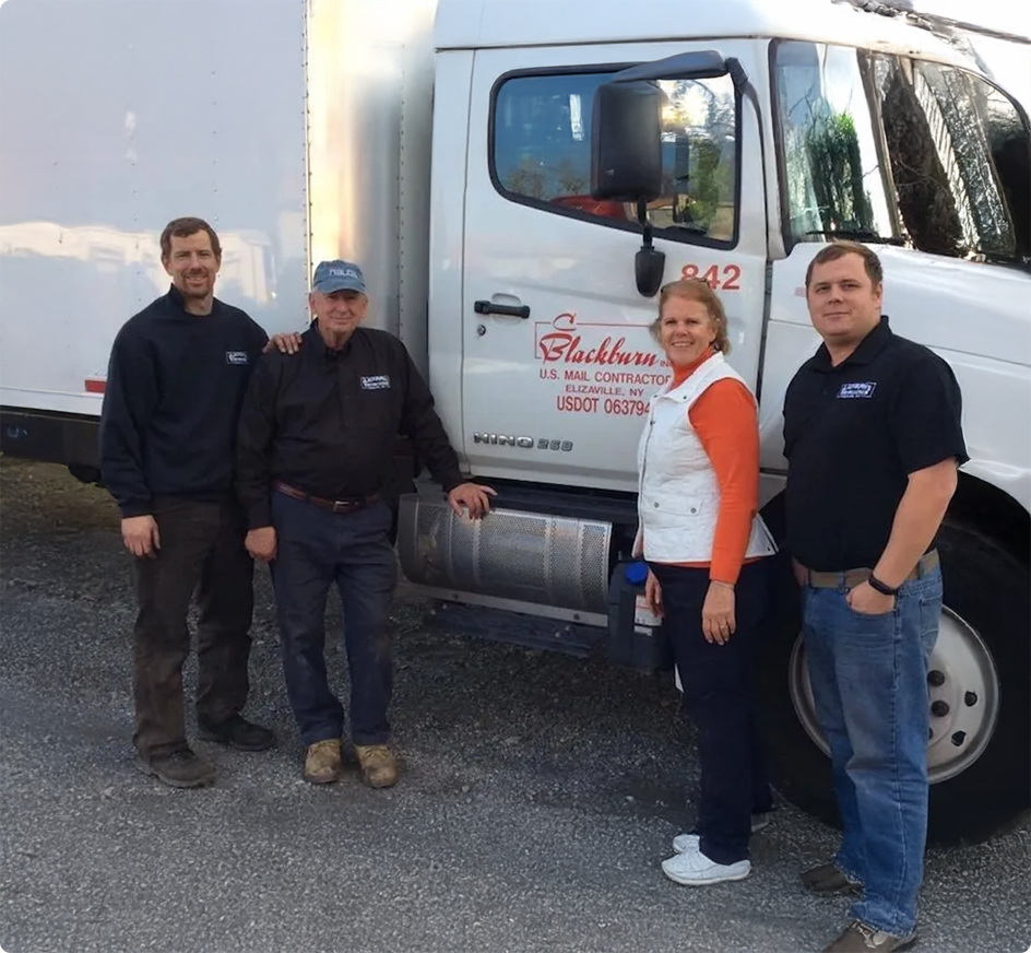 Vier mensen staan naast een witte bestelwagen van een U.S. Mail-contractant in Elizaville, NY.
