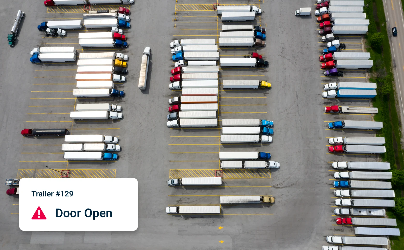Aerial view shows parking lot full of semi-trailer trucks with overlay showing intelligent alert of: Trailer #129 Door Open
