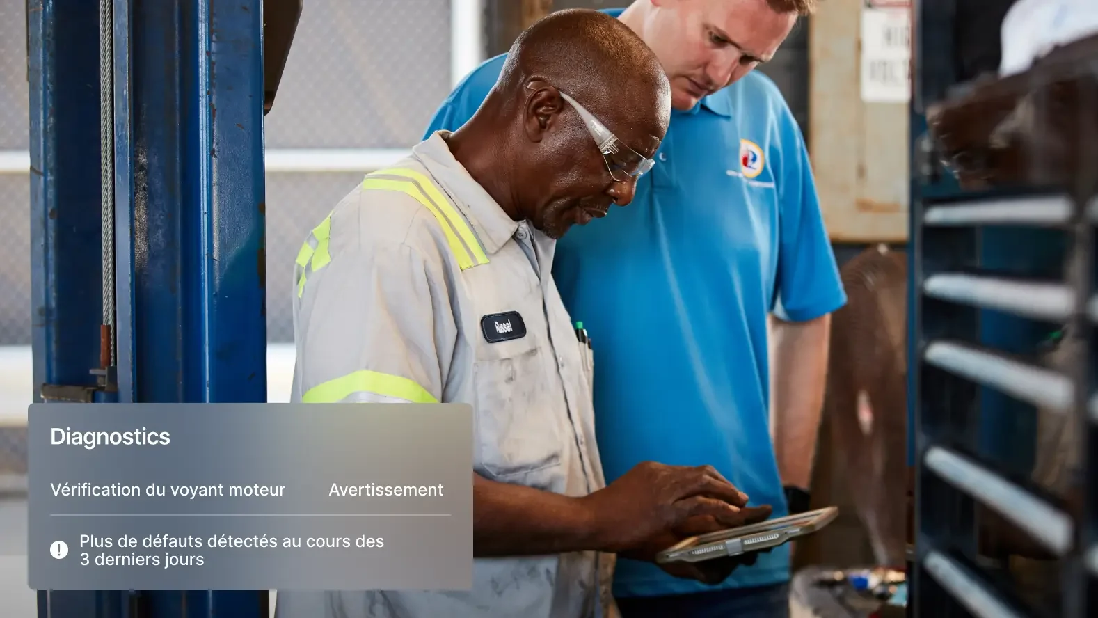 Deux mécaniciens examinent les diagnostics d’un véhicule sur une tablette, avec des alertes sur les voyants du moteur.
