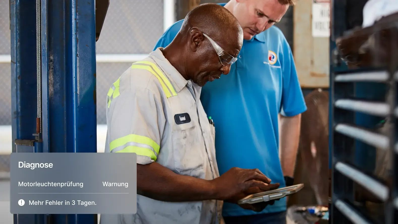 Zwei Mechaniker werten Fahrzeugdiagnose auf Tablet aus: Warnbenachrichtigungen über Motorleuchtenprobleme sichtbar.