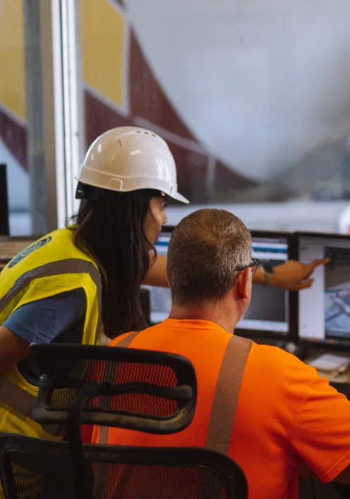 a worker pointing out something in a computer screen to other
