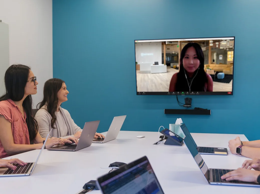 Samsara employees sitting in a conference room looking at a person on a video call.