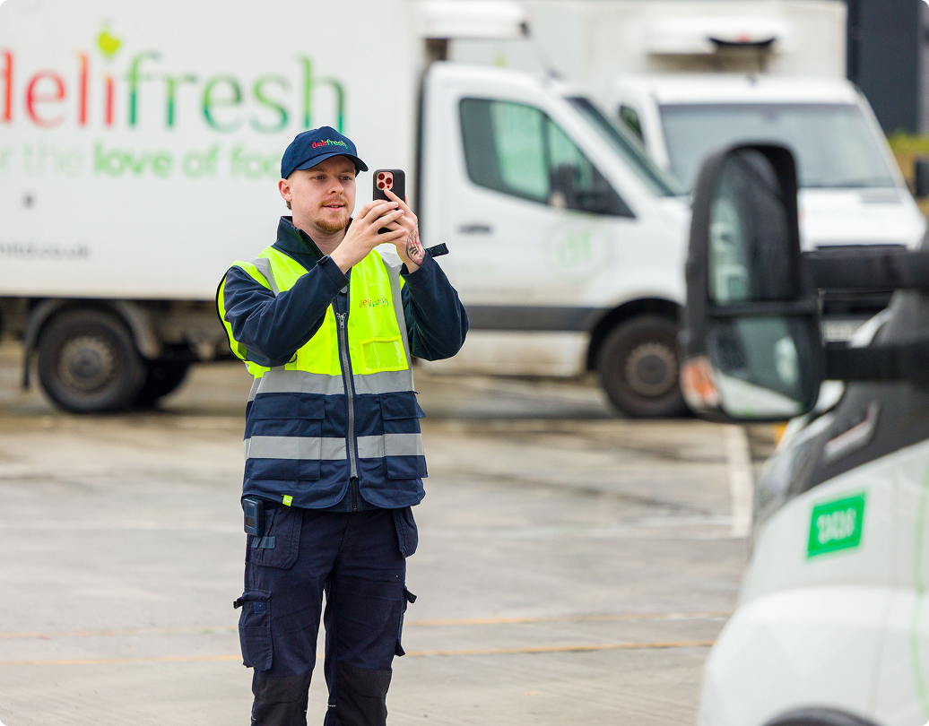 Technicien tenant un colis à côté de machines CNC industrielles dans une installation de fabrication.