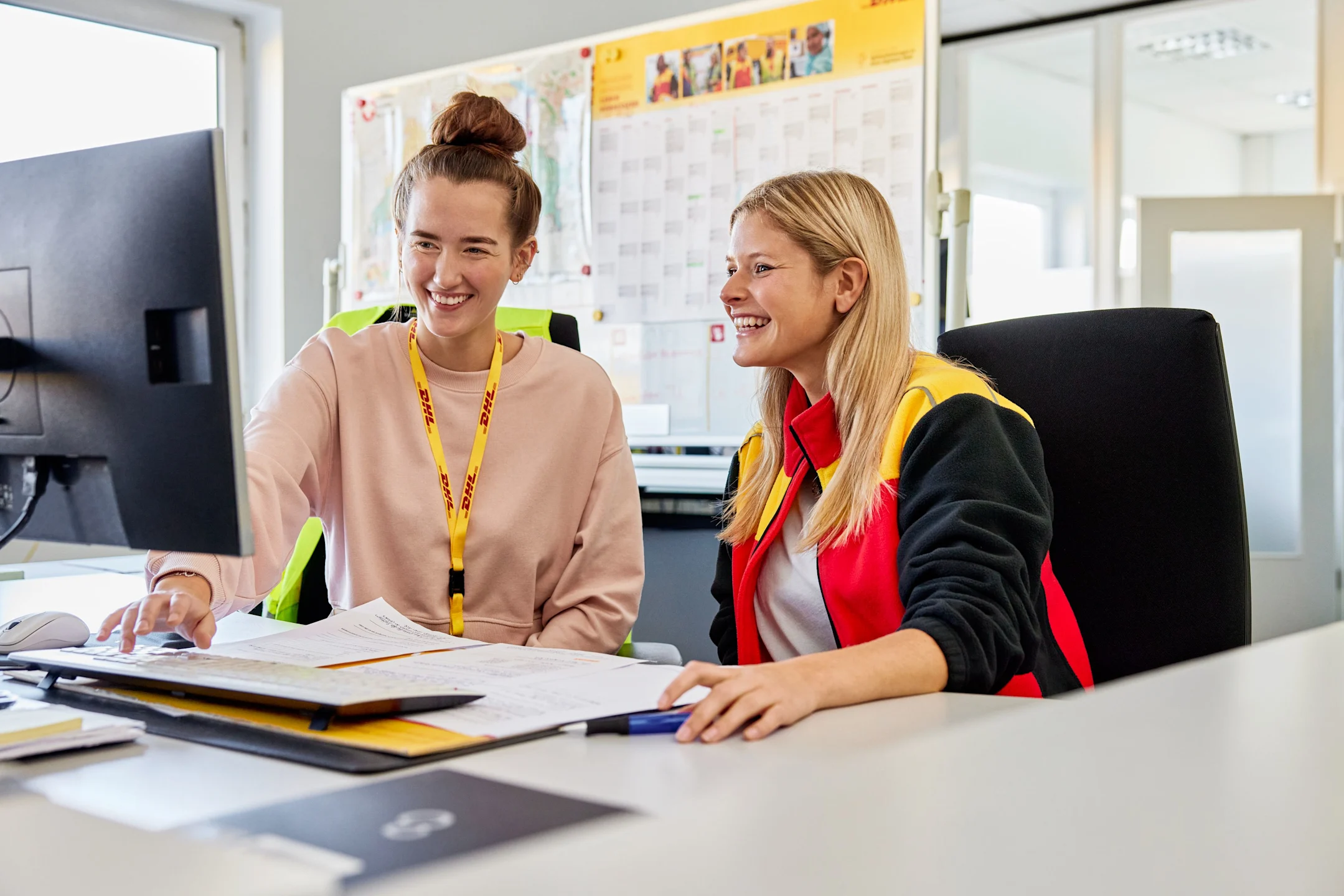 Apprentice explains something to her colleague at the computer.