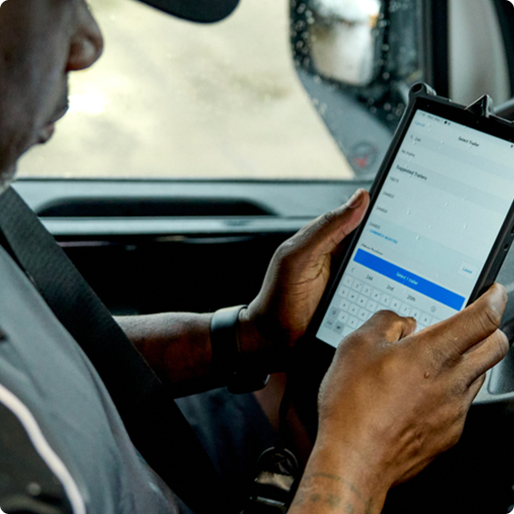 Person using a tablet device inside a vehicle, typing on the digital keyboard while seated in the driver's area.