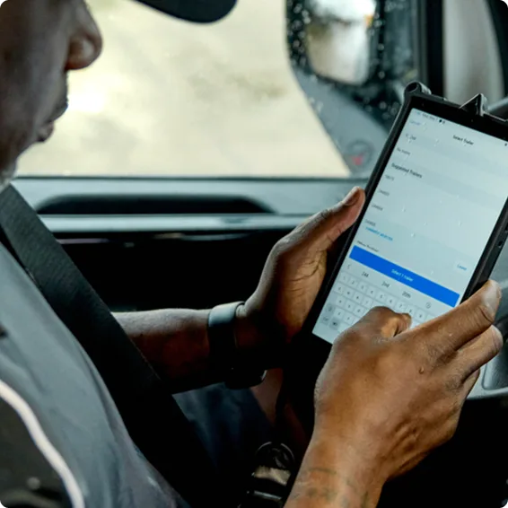 Person using a tablet device inside a vehicle, typing on the digital keyboard while seated in the driver's area.