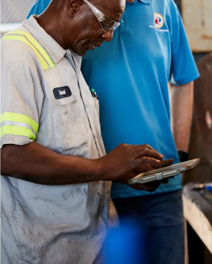 Two workers standing next to each other using the Samsara app on an iPad.