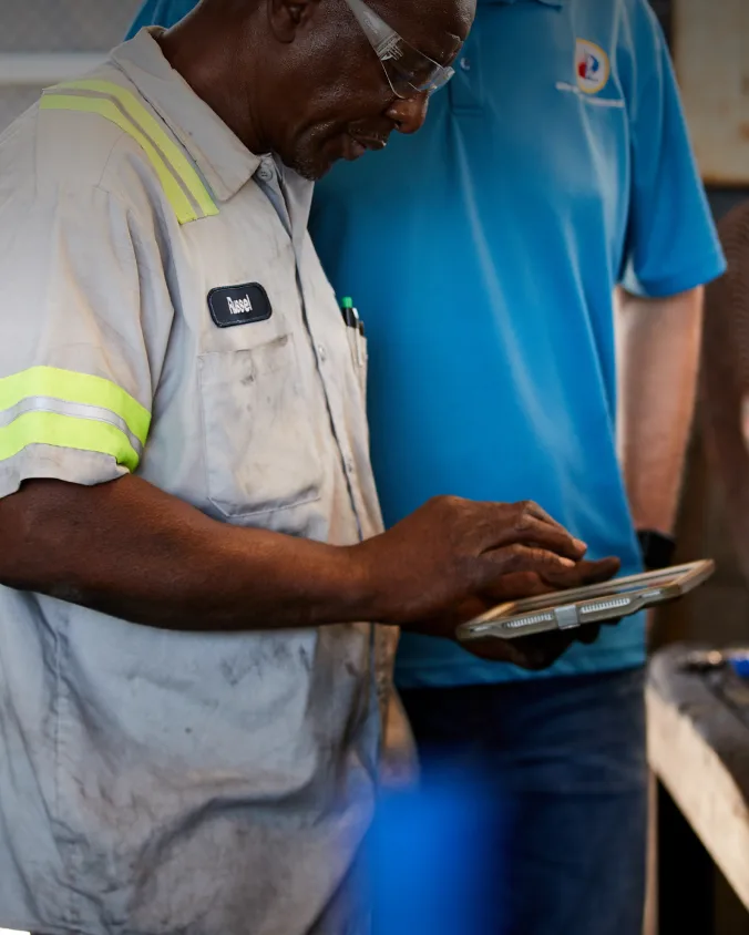 Deux travailleurs debout l'un à côté de l'autre utilisant l'application Samsara sur un iPad.