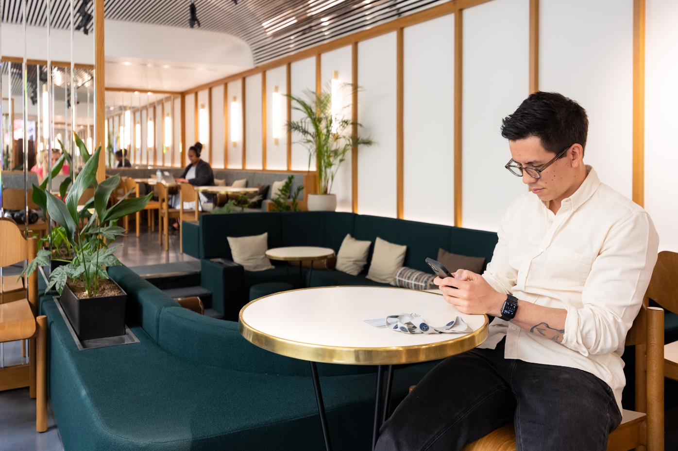 Un employé de Samsara, assis dans un lounge de Samsara en région parisienne, regardant son téléphone.