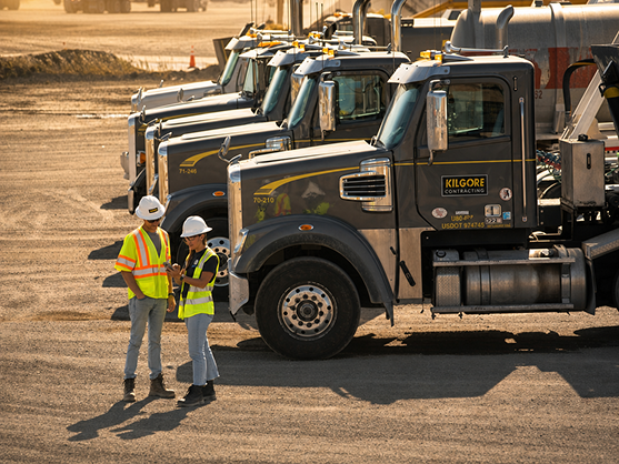 Workers standing near trucks in a yard