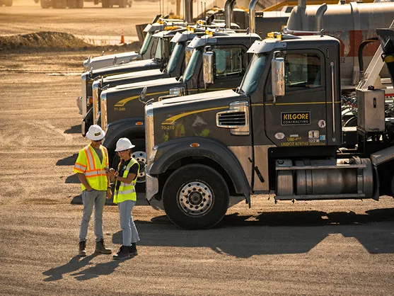 Workers standing near trucks in a yard