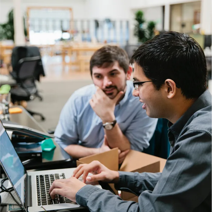 Samsara employees sitting at a desk smiling and working at the computer.