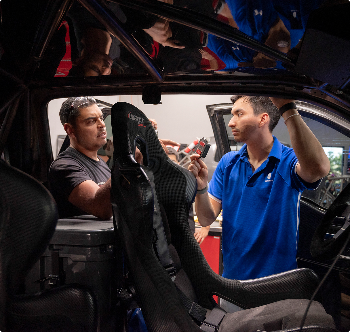 Técnicos instalando asiento deportivo IMPACT en un automóvil. Uno sostiene el asiento mientras otro muestra un componente.