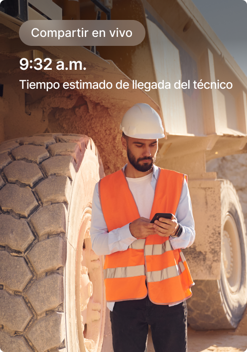 Albañil con chaleco de seguridad naranja ve teléfono junto a equipo con pantalla de tiempo estimado de llegada del técnico.