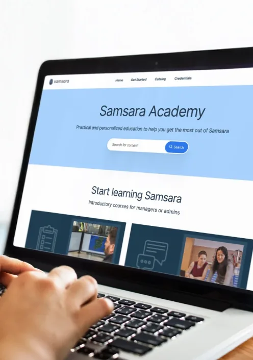 Laptop displaying Samsara Academy website with blue header, search bar, and introductory courses for managers and admins.