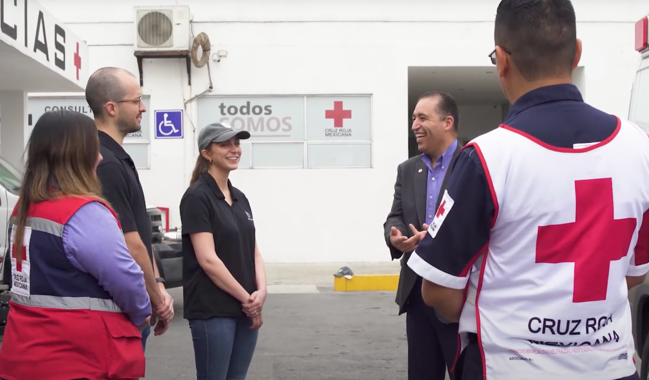 Reunión de grupo fuera del sitio de la Cruz Roja Mexicana con personal y voluntarios en uniforme analizando los servicios.