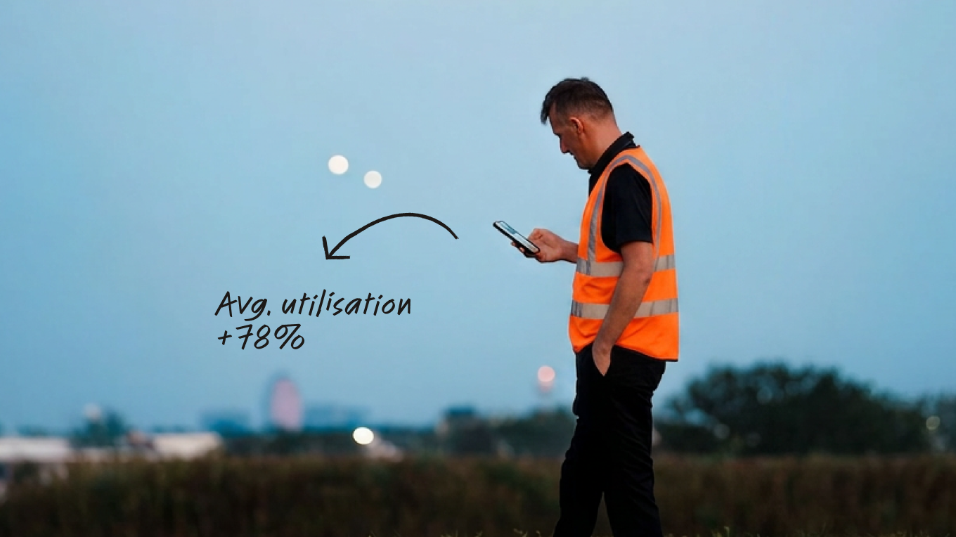 Worker in orange hi-vis vest using a smartphone outdoors at dusk, with text overlay showing avg. utilisation +78%.