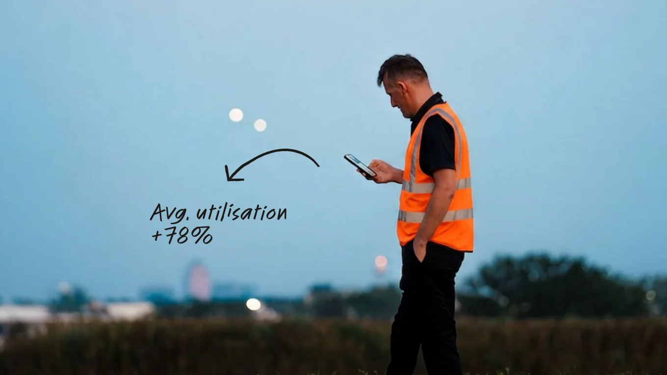 Worker in orange hi-vis vest using a smartphone outdoors at dusk, with text overlay showing avg. utilisation +78%.
