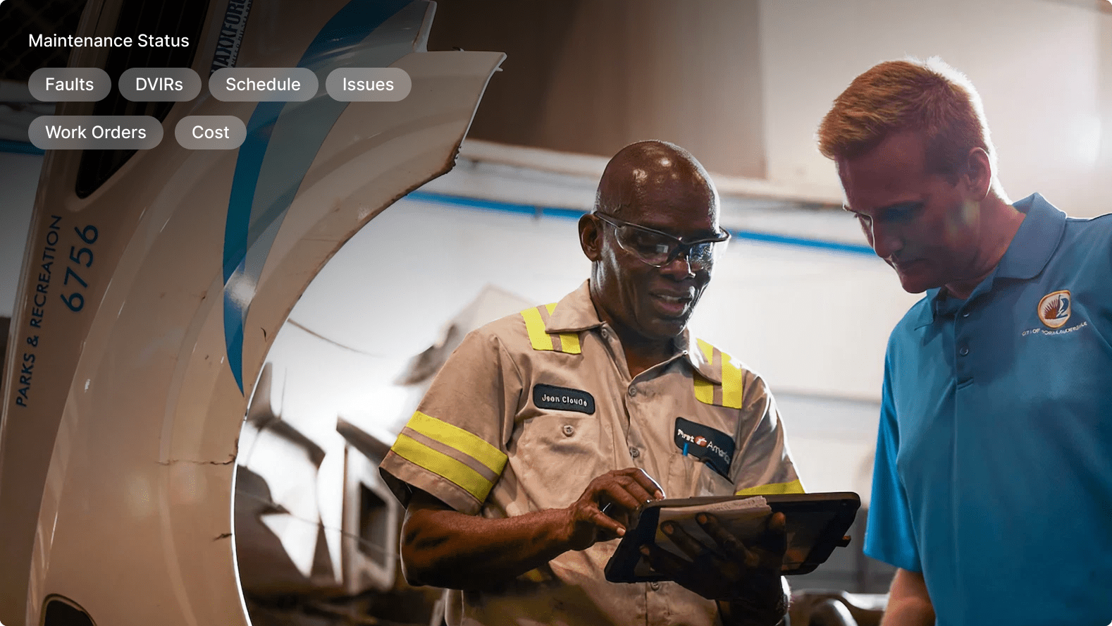 Two maintenance technicians reviewing information on a tablet near an aircraft with maintenance status menu overlay.