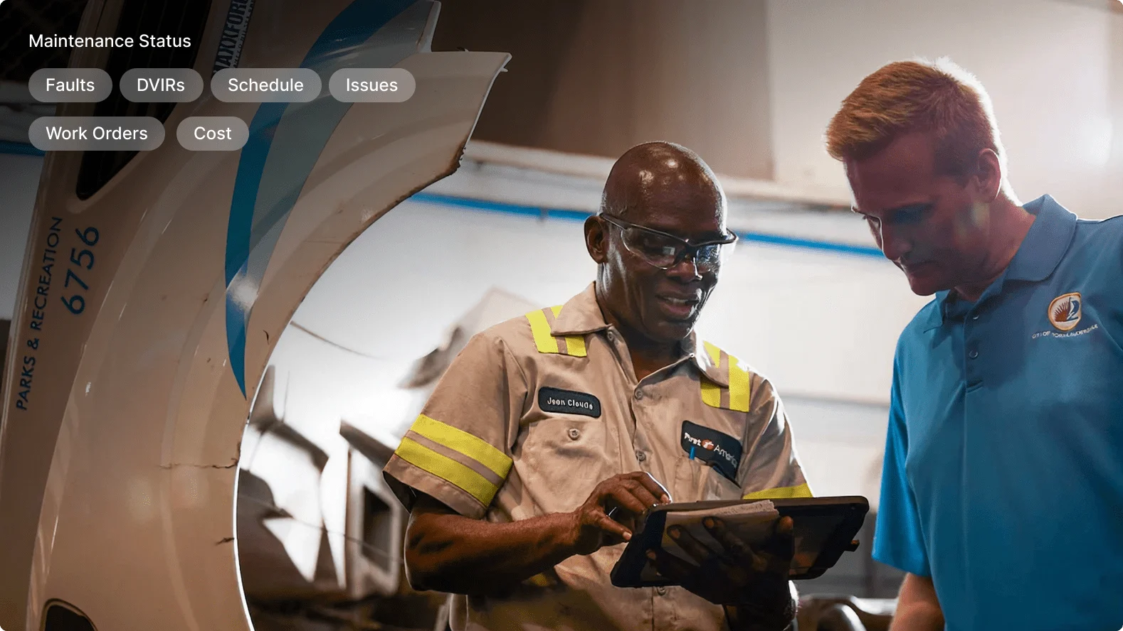 Two maintenance technicians reviewing information on a tablet near an aircraft with maintenance status menu overlay.