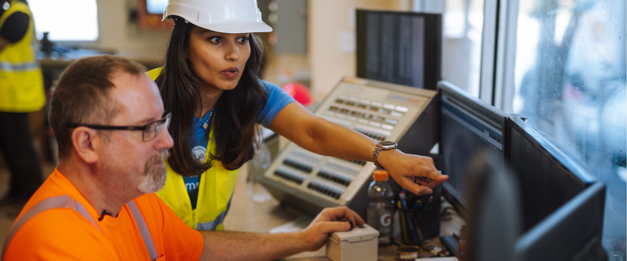 Two people pointing at a monitor.
