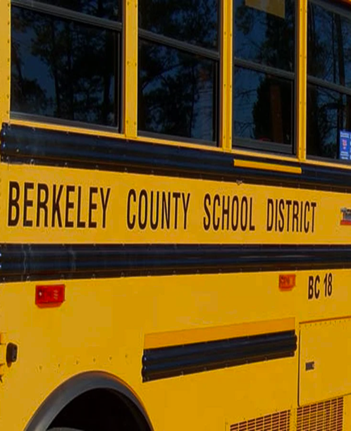 Close-up of a yellow Berkeley County School District bus showing windows and side lettering with bus number BC 18.