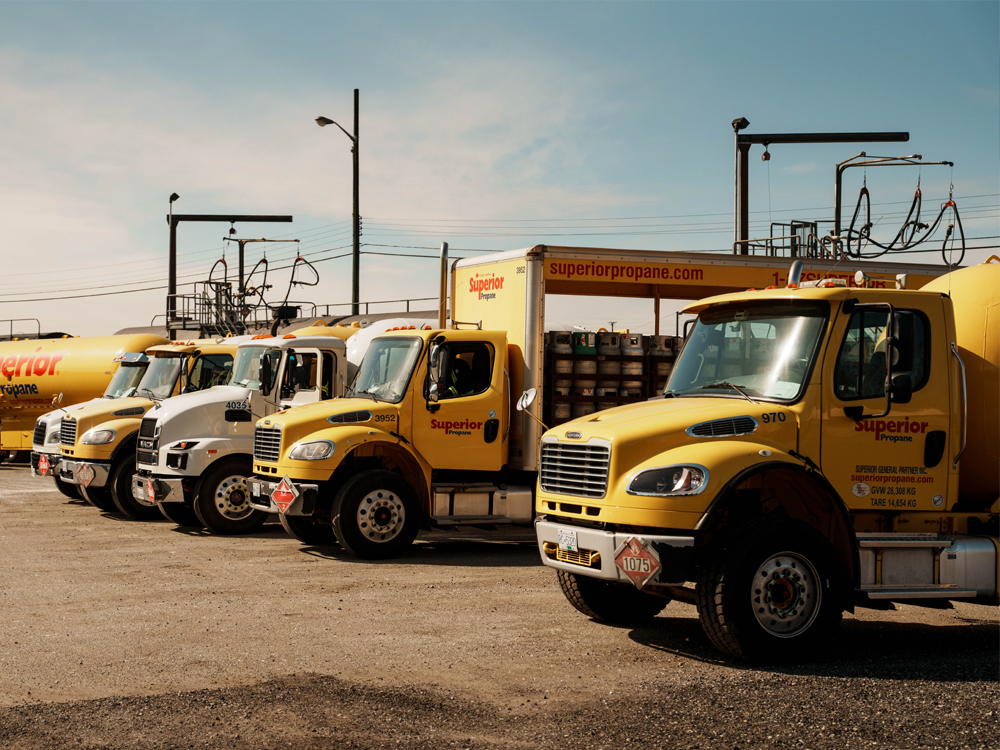 Flotte de camions jaunes Superior Propane stationnés dans une cour, avec réservoirs et équipements de livraison de propane.