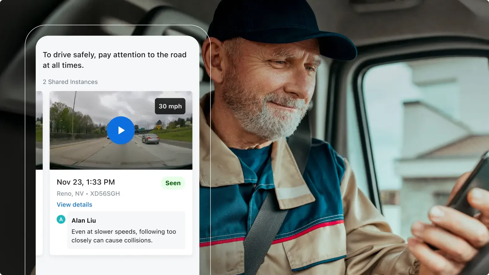 Driver in blue cap checking phone while a safety notification about paying attention to the road appears on screen.