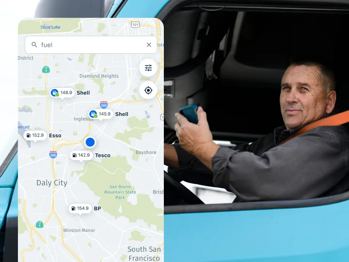 Driver in a blue truck holds a phone beside a map app showing nearby fuel stations with prices.