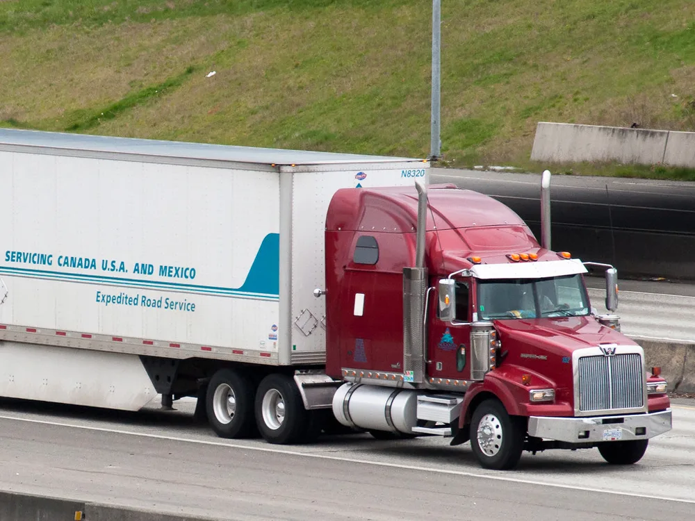 Red Accord Transportation truck with trailer drives down highway