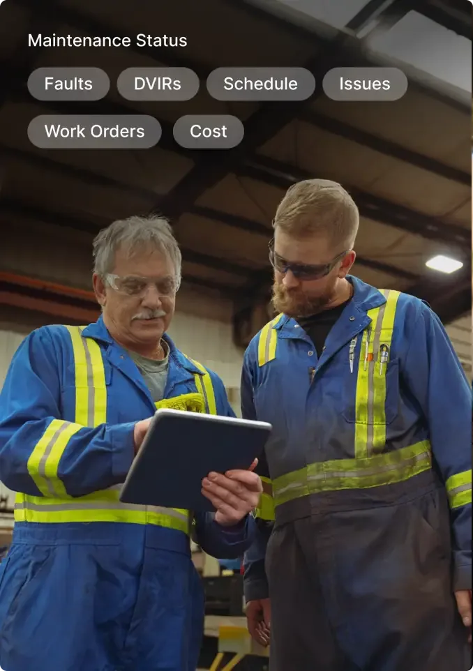 Two maintenance workers in blue uniforms with safety vests reviewing information on a tablet under maintenance status menu.