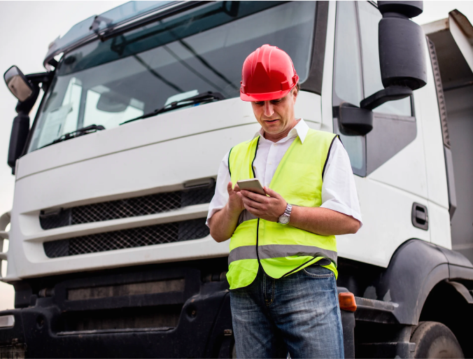Worker standing in front of a truck holding a phone
