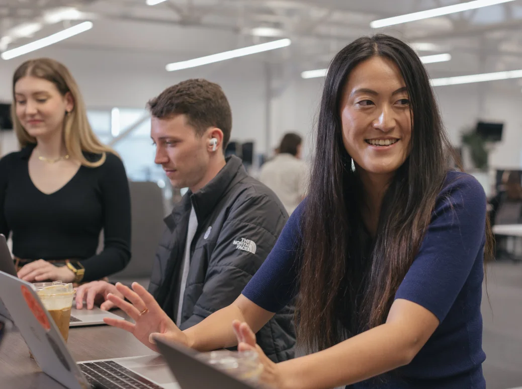 Samsara employees sitting at a desk smiling and working at the computer.