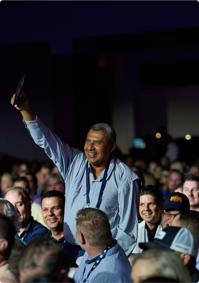 man in crowd standing up smiling and raising hand