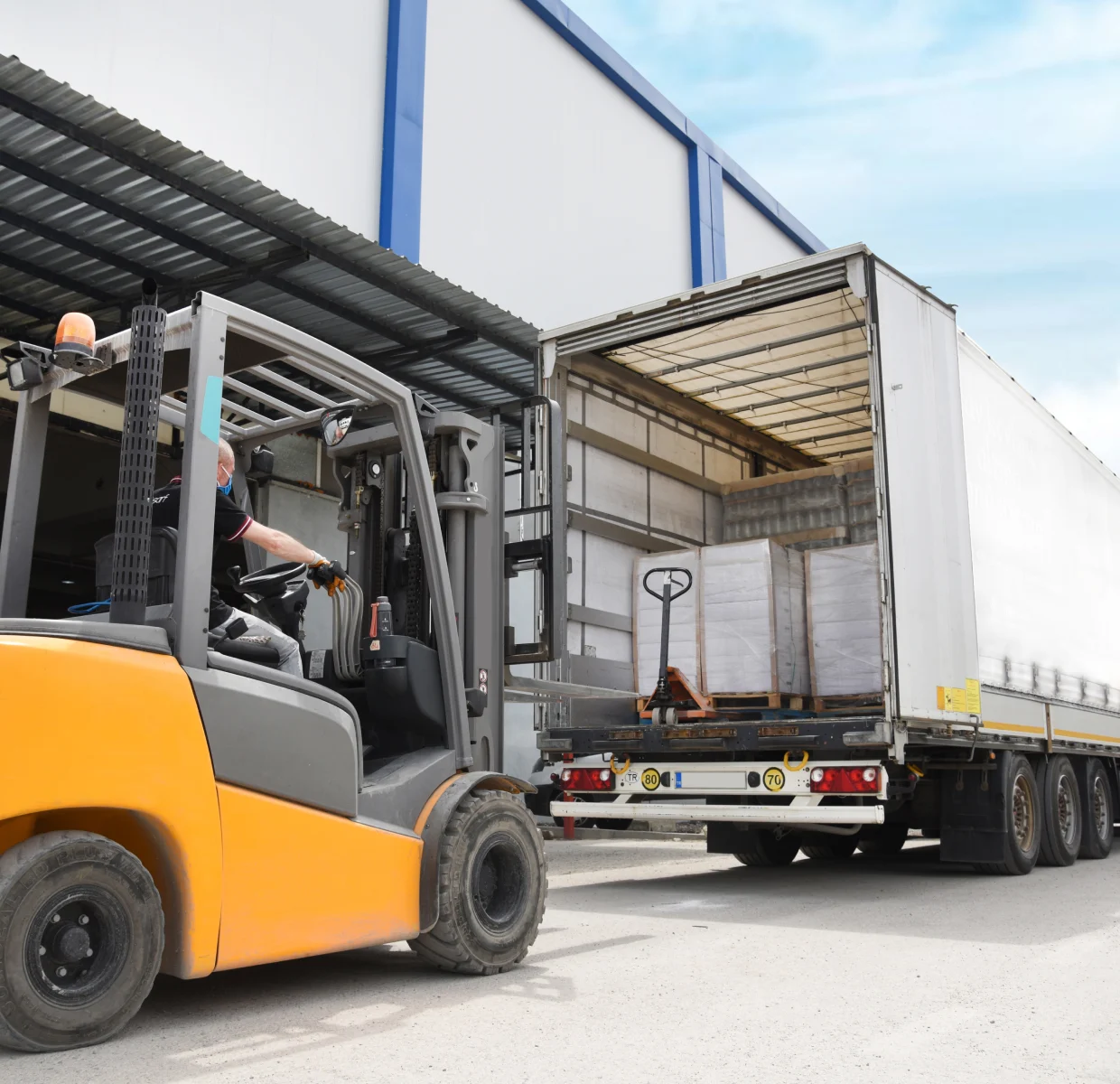 Forklift picking up items from trailer truck