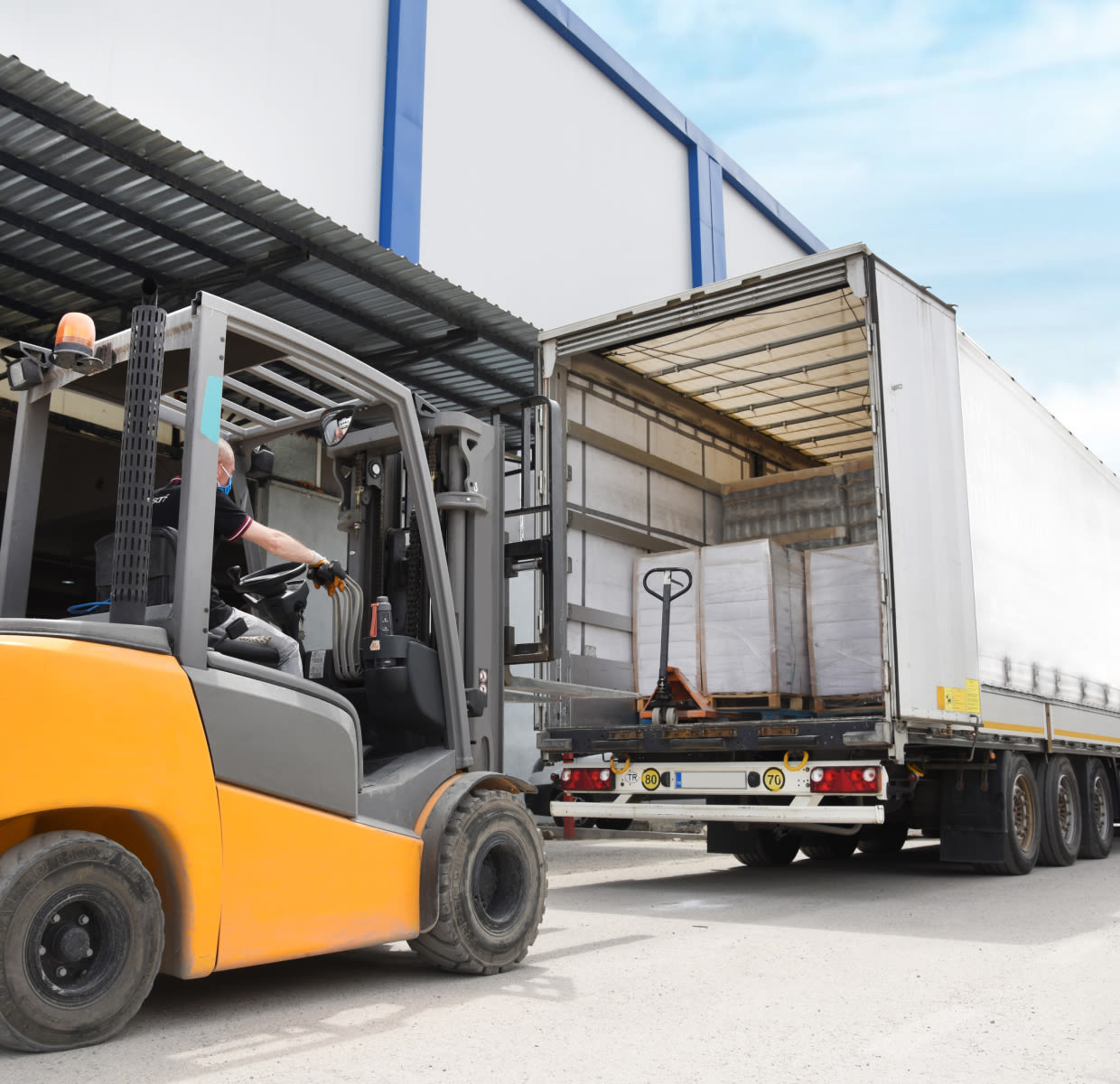 Forklift picking up items from trailer truck