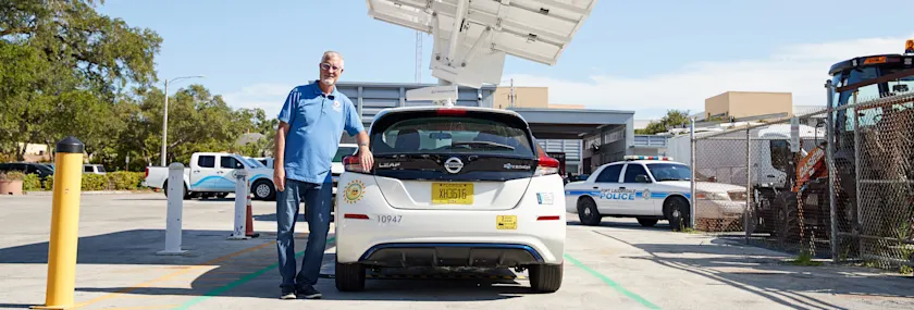 Man with electric vehicle at charging station. 