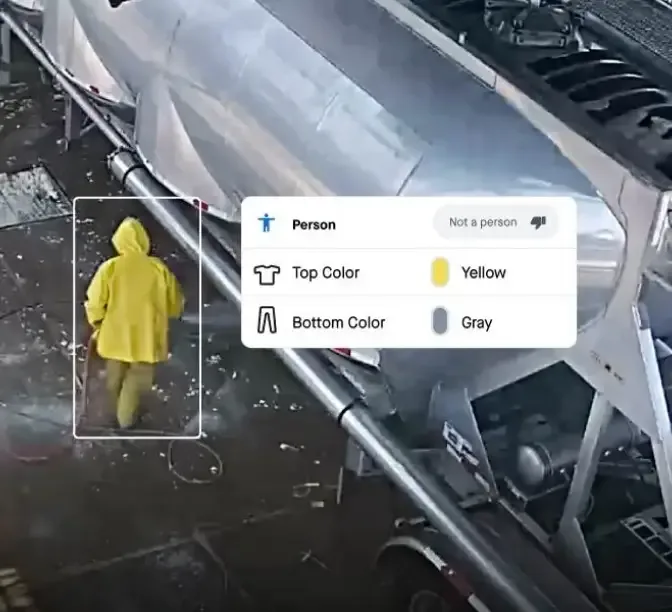 Surveillance footage showing someone in yellow raincoat with AI detection overlay identifying clothing colors.