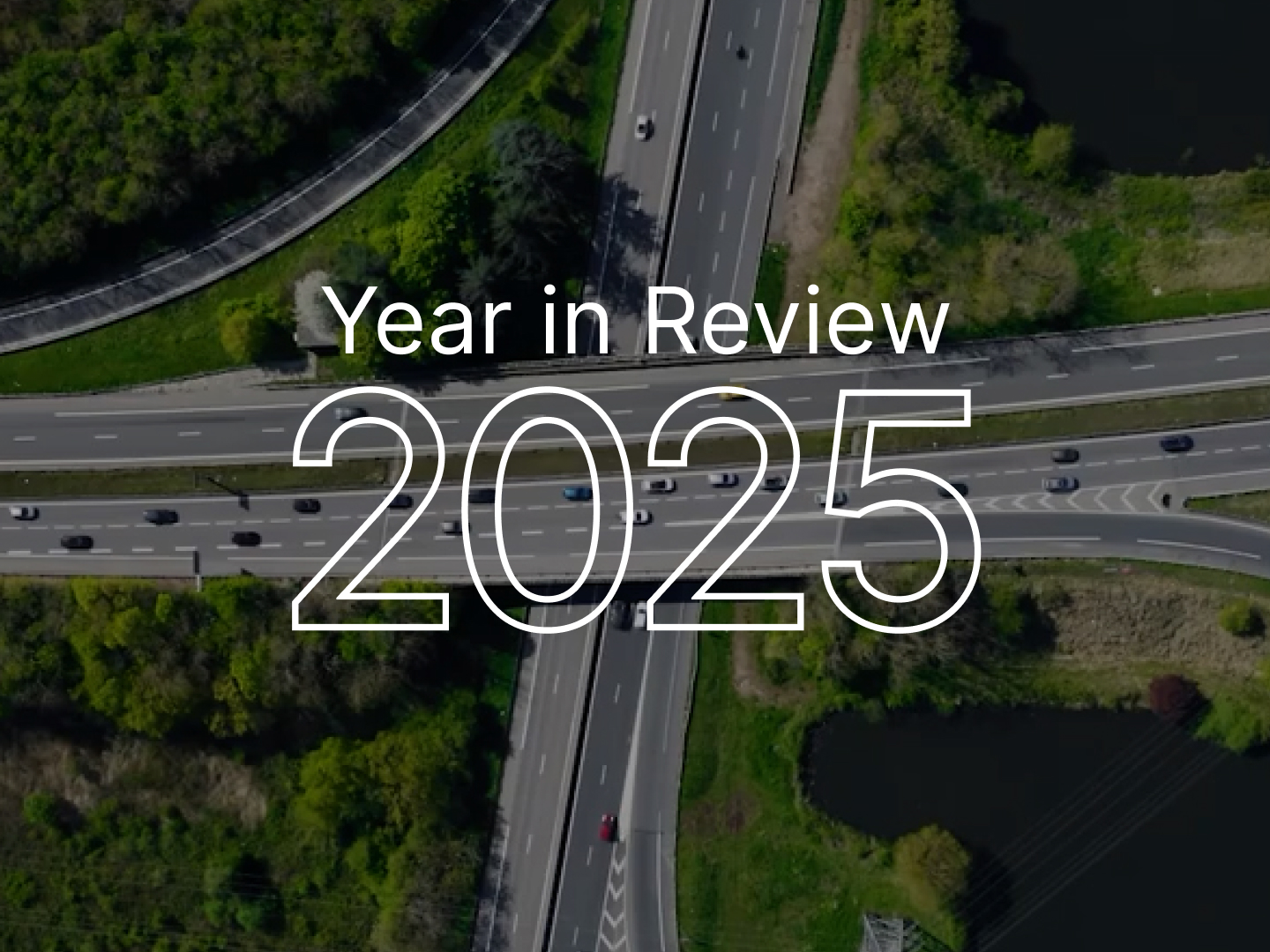 Aerial view of highway intersection with "Year in Review 2025" text overlay on green landscape background.