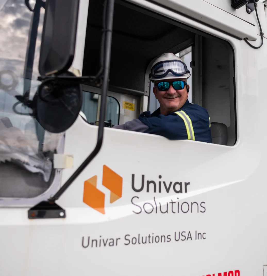 A driver for Univar Solutions smiling out the window of his truck.