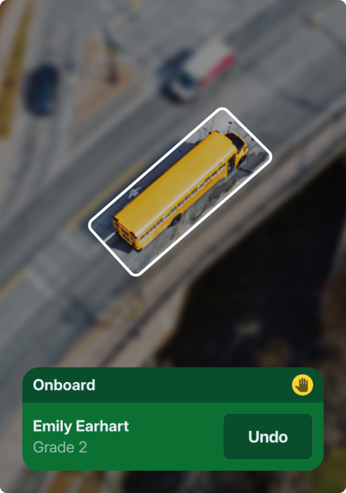 Aerial view of a yellow school bus highlighted on a road, showing pickup at 8:34 AM from 15 Mayfair School Drive.