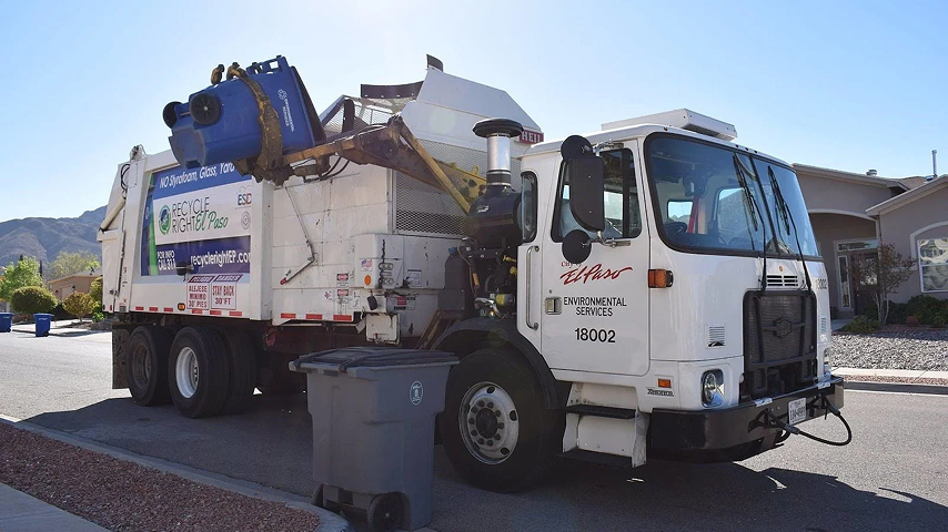 City of El Paso Environmental Services white garbage truck lifting a blue recycling bin on a residential street.