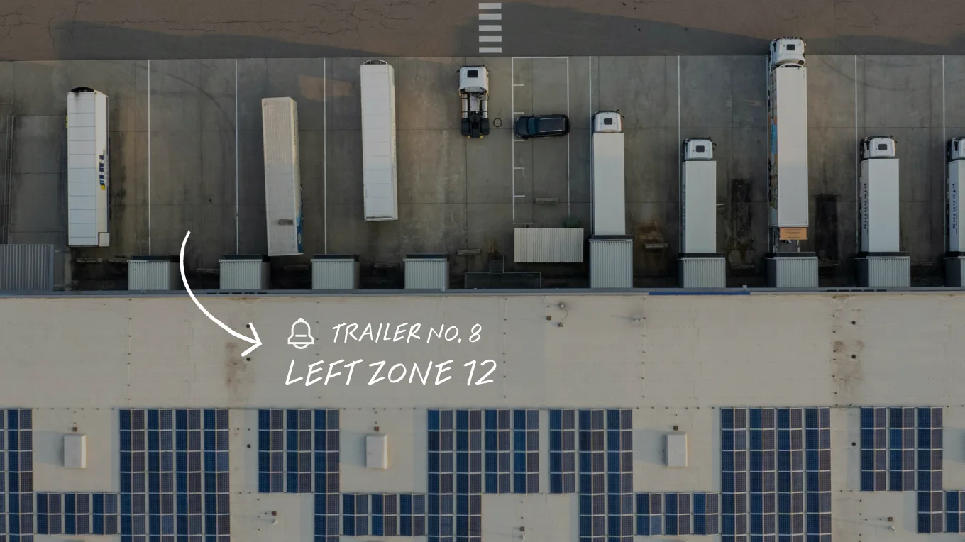 Aerial view of a warehouse loading dock with white trailers, labelled Trailer No. 8, Left Zone 12, with solar panels below.