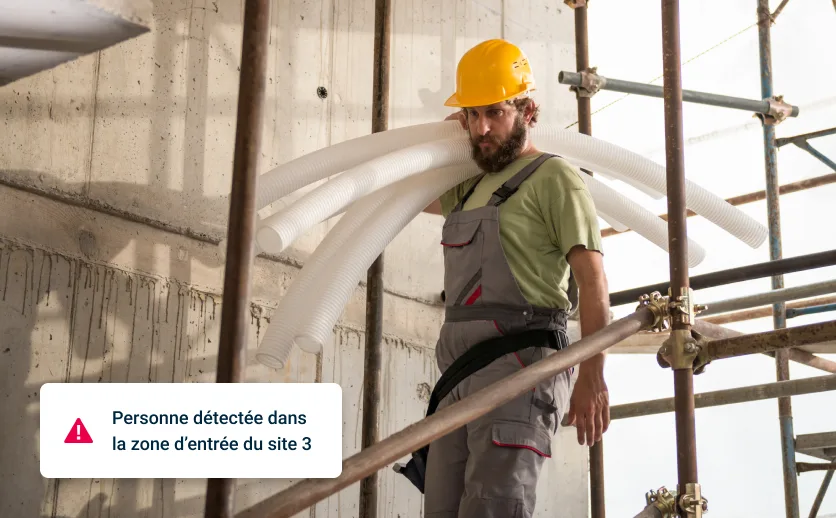 Image de travailleur sur chantier avec superposition montrant l’alerte : « Personne détectée dans zone d’entrée du site 3 »