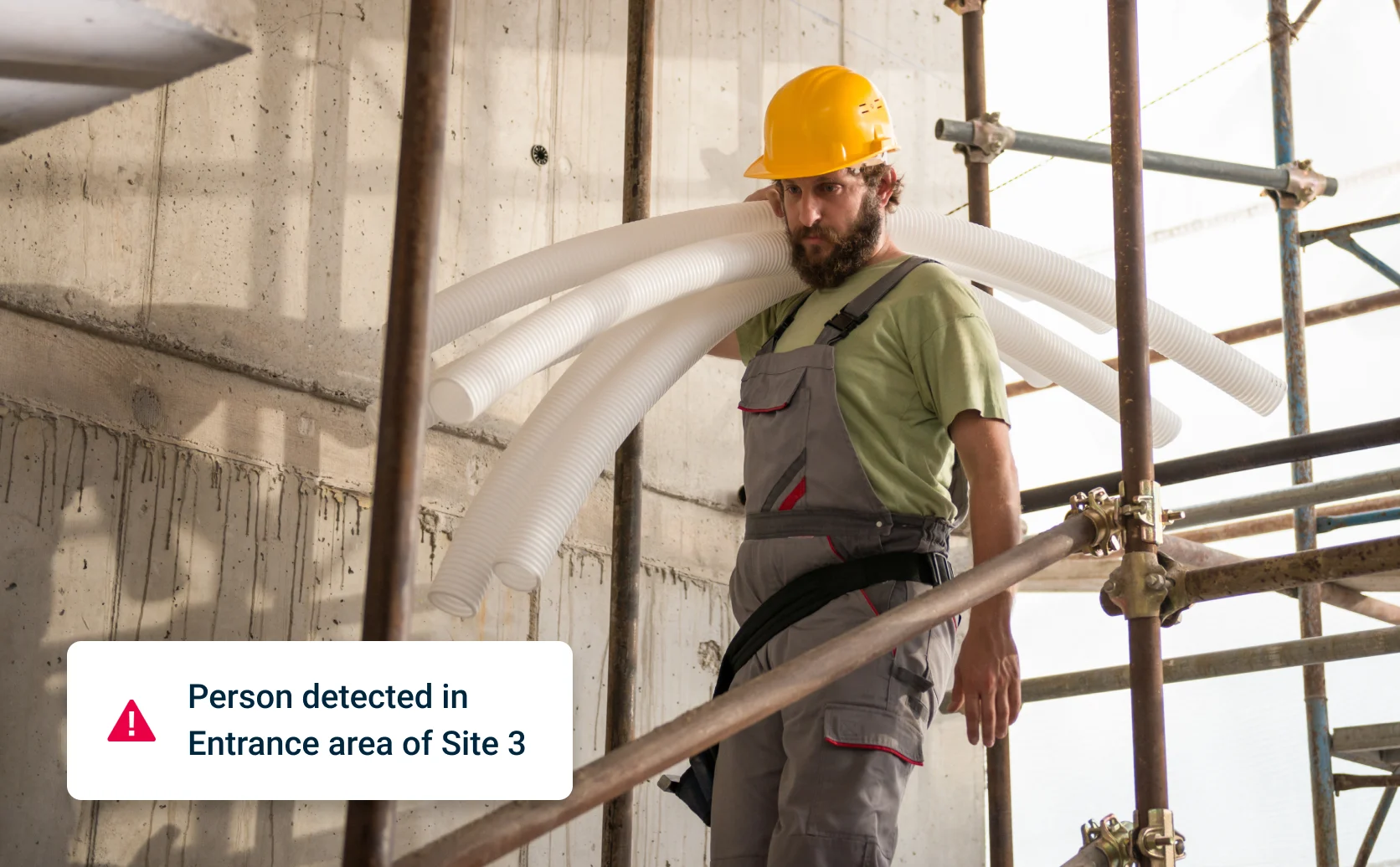 Image of a worker on a job site with an overlay showing the alert: “Person detected in Entrance area of Site 3”