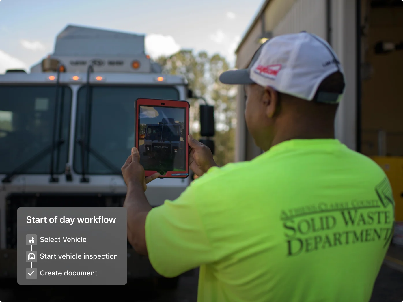 Waste department worker in neon shirt photographing truck with tablet, workflow interface showing vehicle inspection steps.
