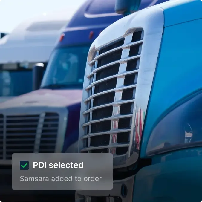 Close-up of blue semi truck grille with other trucks in background and PDI selection notification overlay.
