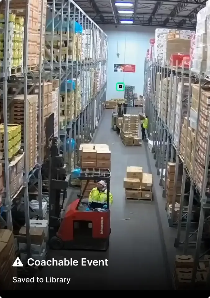 Warehouse workers operating forklifts between tall storage racks filled with stacked boxes and pallets of inventory.